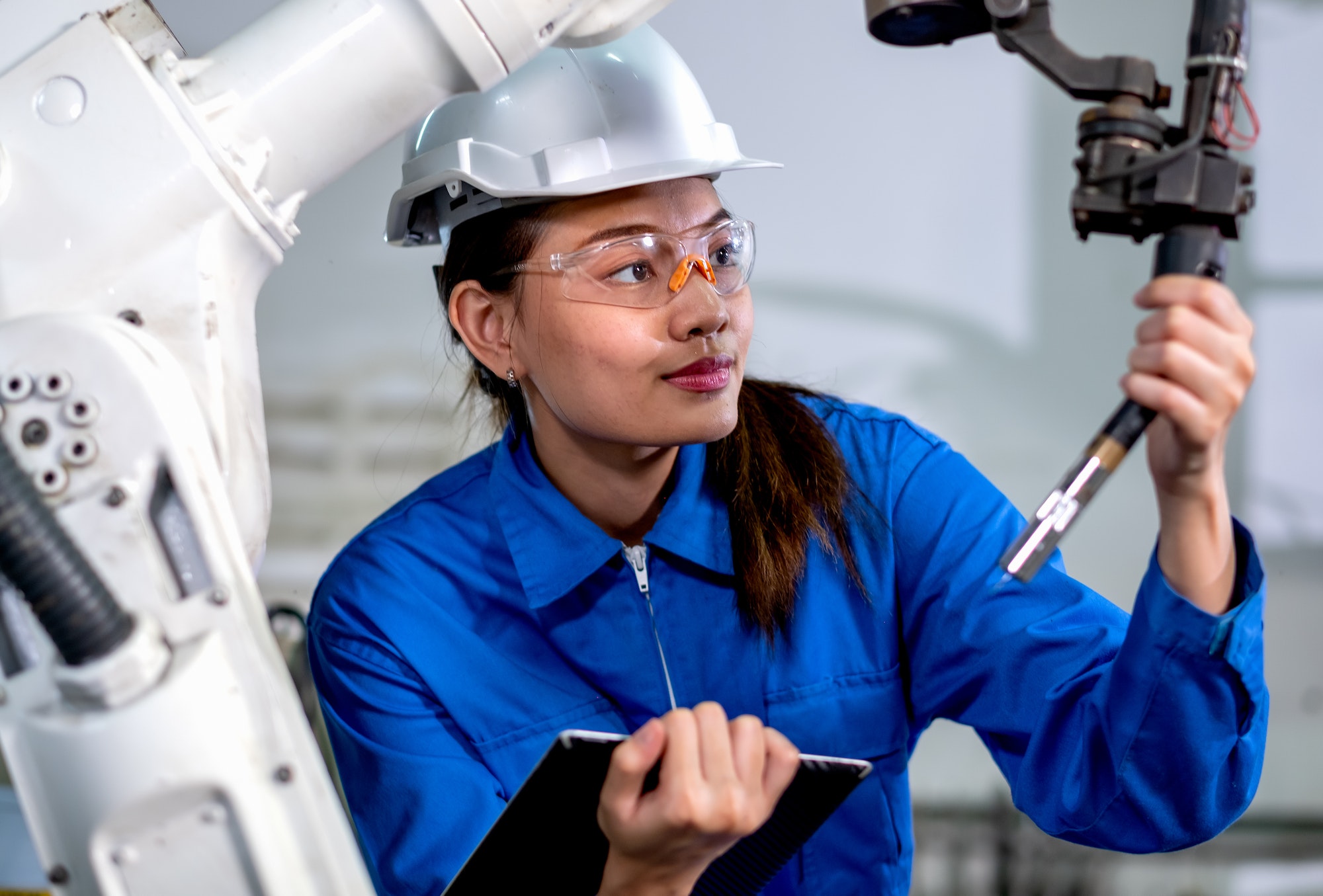 Close up factory worker woman maintenance and check part of robotic machine