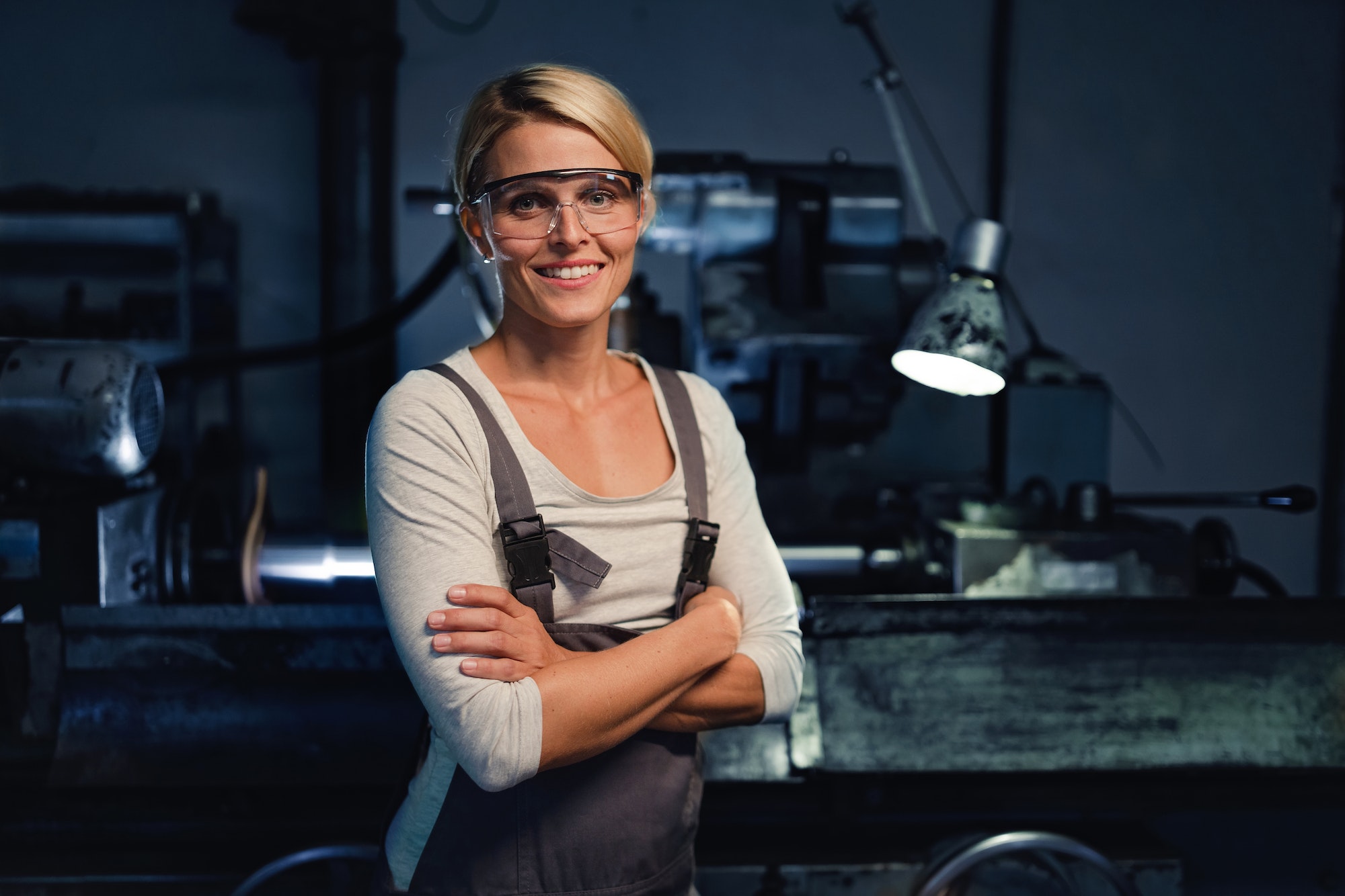 Portrait of mid adult industrial woman working indoors in metal workshop, looking at camera